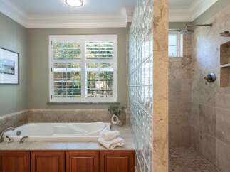 Indulge in luxury with this stunning bathroom featuring a deep soaking tub and a spacious walk-in shower with dual showerheads.