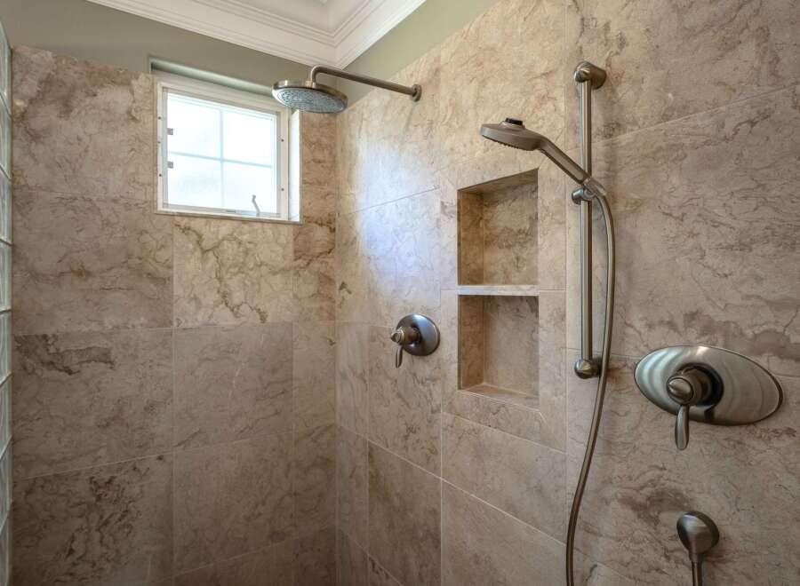 Experience luxury in this stunning shower featuring elegant marble tile and a built-in niche for convenient storage.