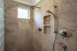 Experience luxury in this stunning shower featuring elegant marble tile and a built-in niche for convenient storage.