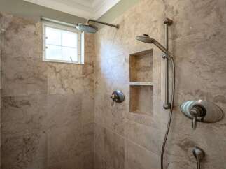 Experience luxury in this stunning shower featuring elegant marble tile and a built-in niche for convenient storage.