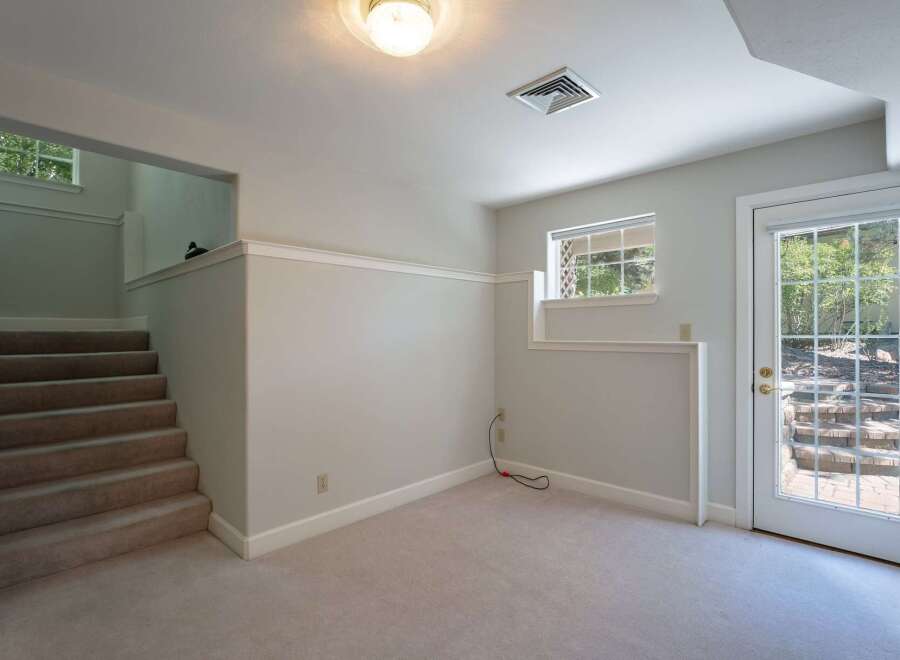 Discover this inviting space featuring a carpeted staircase leading to an upper level with a charming window view.