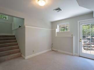 Discover this inviting space featuring a carpeted staircase leading to an upper level with a charming window view.