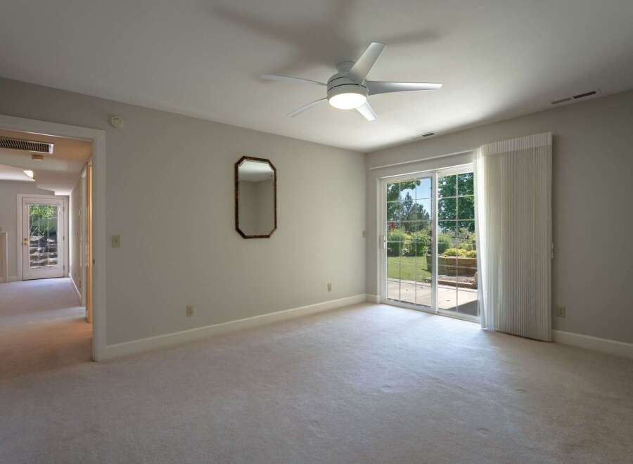 Step into this spacious bedroom featuring plush carpeting and a modern ceiling fan for ultimate comfort.
