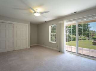 Step into this spacious bedroom featuring a modern ceiling fan and ample closet space behind elegant double doors.