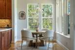 Enjoy meals in this bright dining area, featuring a round wooden table surrounded by four upholstered chairs with gold accents.