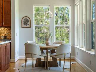 Enjoy meals in this bright dining area, featuring a round wooden table surrounded by four upholstered chairs with gold accents.