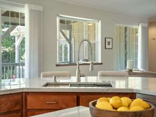 Experience luxury in this stunning kitchen featuring a sleek marble countertop and a modern faucet.