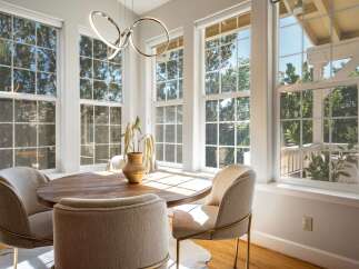 Bathed in natural light, this charming dining area features a round wooden table surrounded by comfortable upholstered chairs.