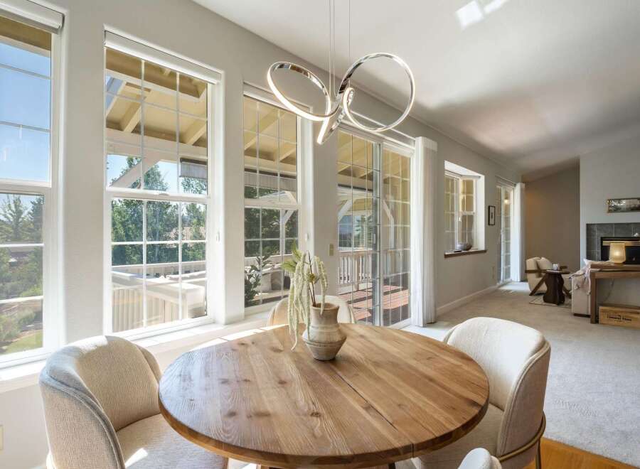Bright and airy dining area featuring a round wooden table with comfortable upholstered chairs, perfect for intimate meals.