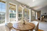Bright and airy dining area featuring a round wooden table with comfortable upholstered chairs, perfect for intimate meals.