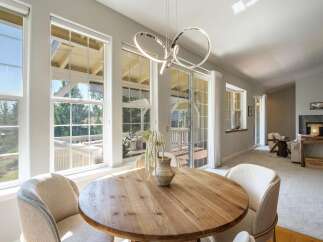 Bright and airy dining area featuring a round wooden table with comfortable upholstered chairs, perfect for intimate meals.