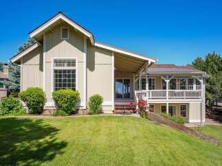 This charming home features a light beige exterior with white trim and a durable metal roof.