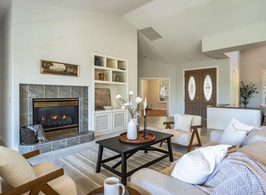 Step into this inviting living room, centered around a cozy fireplace with elegant tile surround and built-in shelving.