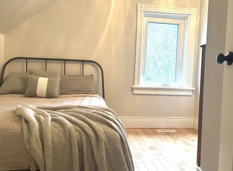 Discover this charming bedroom featuring a cozy bed with plush pillows and a soft throw blanket, perfect for relaxation.