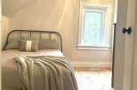 Discover this charming bedroom featuring a cozy bed with plush pillows and a soft throw blanket, perfect for relaxation.