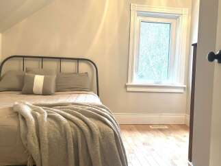 Discover this charming bedroom featuring a cozy bed with plush pillows and a soft throw blanket, perfect for relaxation.