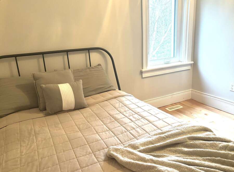 Discover comfort and style in this inviting bedroom, featuring a cozy bed adorned with plush pillows and a soft, quilted comforter.