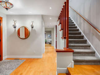 Step into this inviting entryway, showcasing a beautiful staircase and warm hardwood floors.