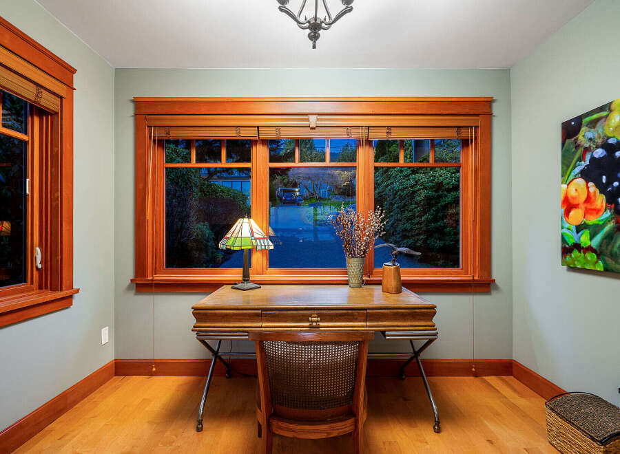 Step into this inviting home office, featuring stunning natural light and elegant wood accents.