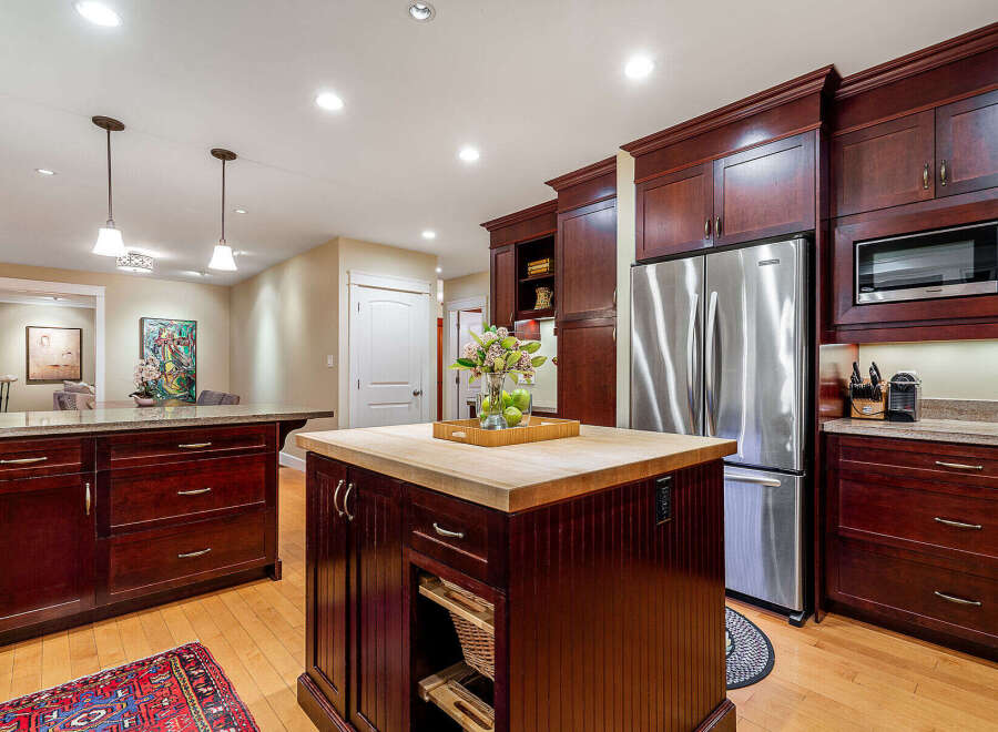 This stunning kitchen boasts rich, dark wood cabinetry and a spacious island with a butcher block countertop, perfect for meal preparation and entertaining.