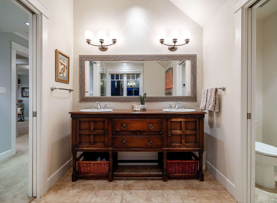 This stunning bathroom features a beautiful wooden vanity with dual sinks, offering ample storage and a touch of classic elegance.