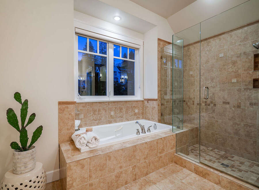 Indulge in luxury within this stunning bathroom, featuring a spacious soaking tub and a separate glass-enclosed shower.