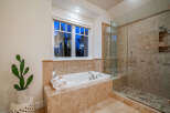 Indulge in luxury within this stunning bathroom, featuring a spacious soaking tub and a separate glass-enclosed shower.