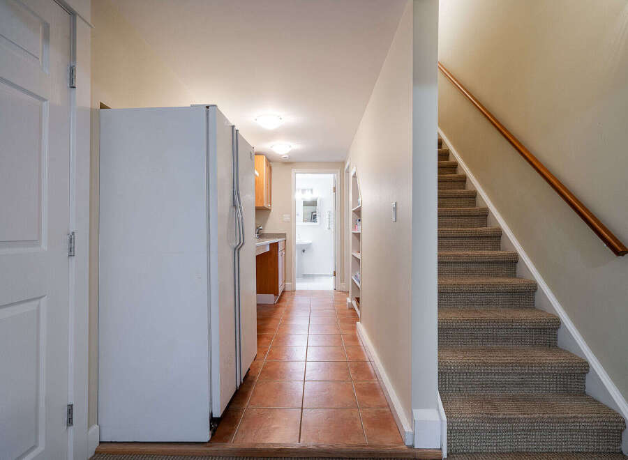 Step into this inviting space featuring a well-lit hallway with a kitchen and staircase.