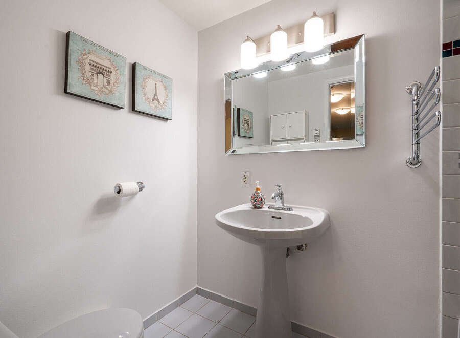 This charming bathroom features a pedestal sink, a large mirror, and stylish wall art.