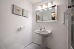 This charming bathroom features a pedestal sink, a large mirror, and stylish wall art.