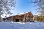Discover the charm of this stunning wooden chalet nestled in a snowy landscape.