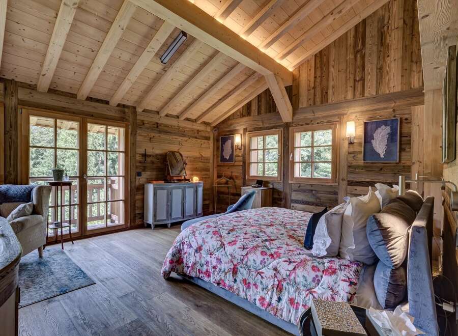 Experience rustic elegance in this stunning bedroom featuring exposed wooden beams and walls, creating a warm and inviting atmosphere.