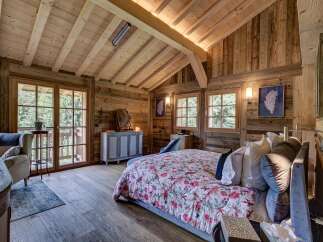 Experience rustic elegance in this stunning bedroom featuring exposed wooden beams and walls, creating a warm and inviting atmosphere.