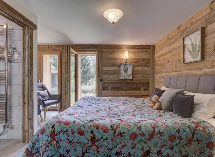 Experience the charm of this cozy bedroom, featuring a stunning wooden accent wall and a vibrant floral quilt.