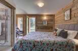 Experience the charm of this cozy bedroom, featuring a stunning wooden accent wall and a vibrant floral quilt.