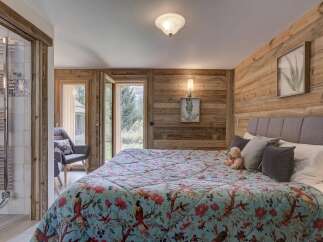 Experience the charm of this cozy bedroom, featuring a stunning wooden accent wall and a vibrant floral quilt.