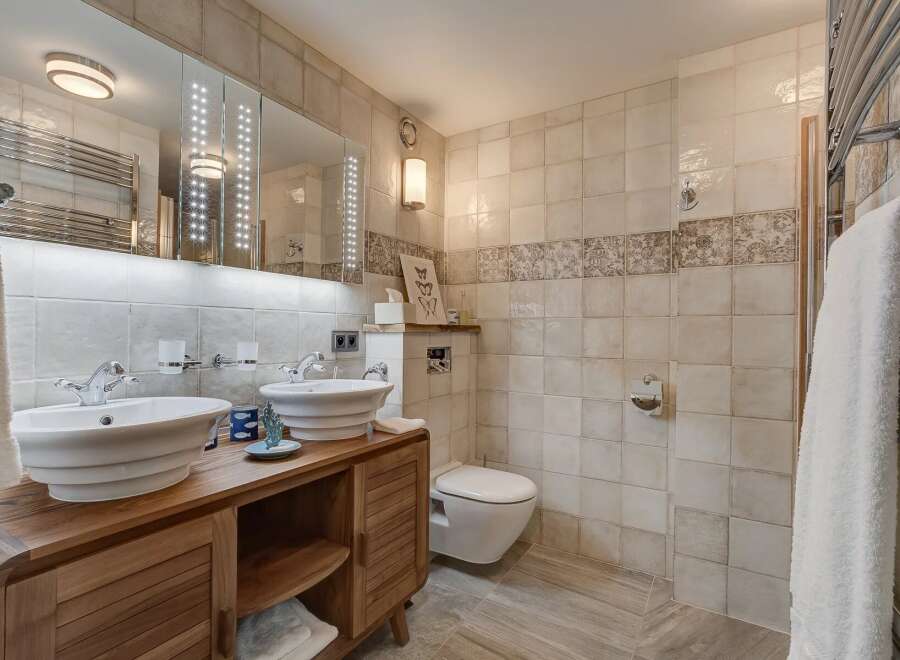 This luxurious bathroom features a double vanity with stylish vessel sinks, set atop a beautiful wooden cabinet.