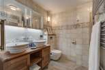 This luxurious bathroom features a double vanity with stylish vessel sinks, set atop a beautiful wooden cabinet.
