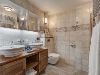 This luxurious bathroom features a double vanity with stylish vessel sinks, set atop a beautiful wooden cabinet.