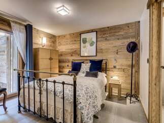 This stunning bedroom boasts a rustic charm with its wood-paneled walls and elegant iron bed frame.
