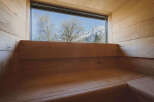 Experience tranquility in this stunning sauna, featuring panoramic views of snow-capped mountains and lush trees.
