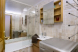 This charming bathroom boasts a modern aesthetic with beige tile, a glass-enclosed shower, and a built-in vanity with a washing machine.
