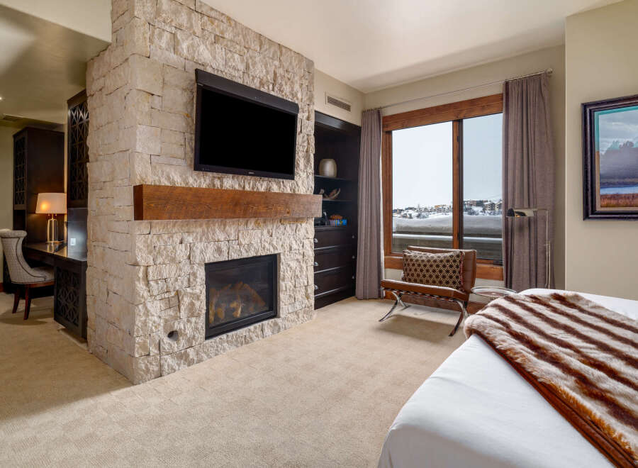 Experience luxury living in this stunning bedroom featuring a cozy fireplace and a sleek TV.