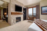 Experience luxury living in this stunning bedroom featuring a cozy fireplace and a sleek TV.