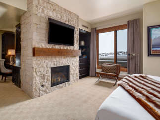 Experience luxury living in this stunning bedroom featuring a cozy fireplace and a sleek TV.