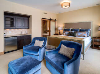 Step into luxury with this stunning bedroom, featuring a private wet bar and elegant seating area.