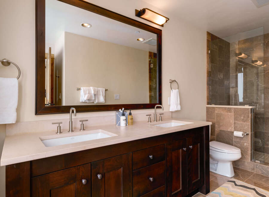 This luxurious bathroom boasts a stunning dark wood vanity with dual sinks, offering ample space and storage.