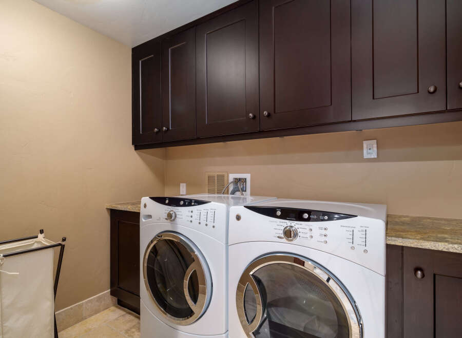 This laundry room features a modern design with dark wood cabinetry and a neutral color palette.