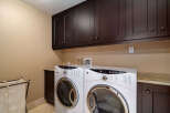 This laundry room features a modern design with dark wood cabinetry and a neutral color palette.