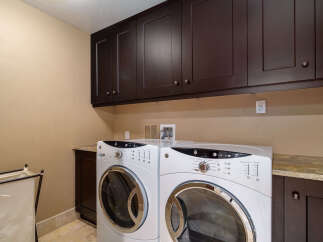 This laundry room features a modern design with dark wood cabinetry and a neutral color palette.